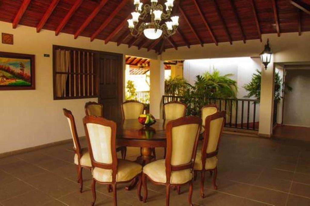 Comedor redondo bajo techo de madera, con sillas tapizadas y candelabro