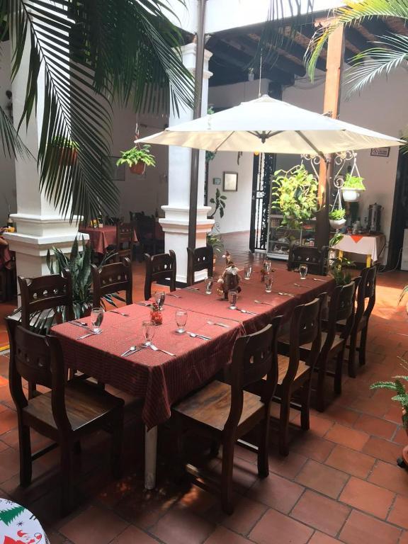 Salón comedor con mesa larga, mantel rojo a cuadros y plantas tropicales
