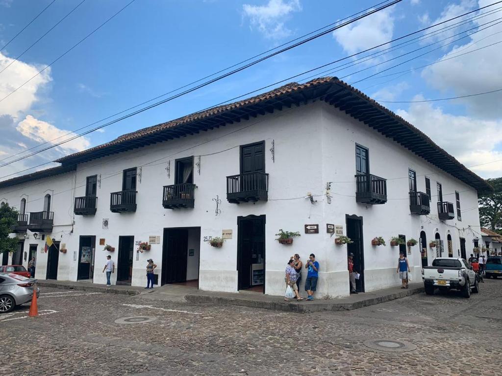 Fachada colonial blanca con balcones de madera oscura en una esquina de Girón